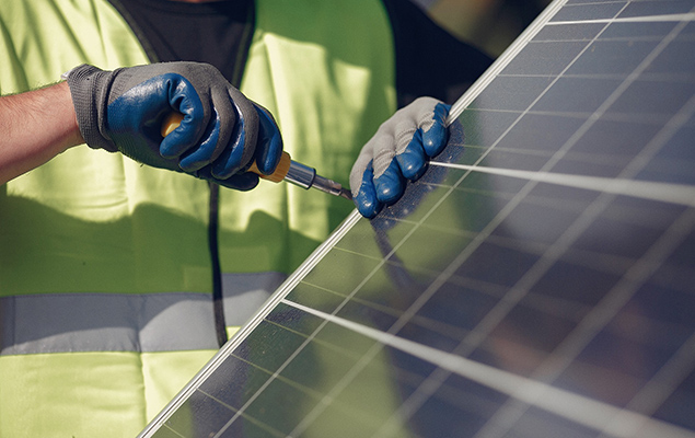 Solartechniker schraubt an einer PV-Anlage